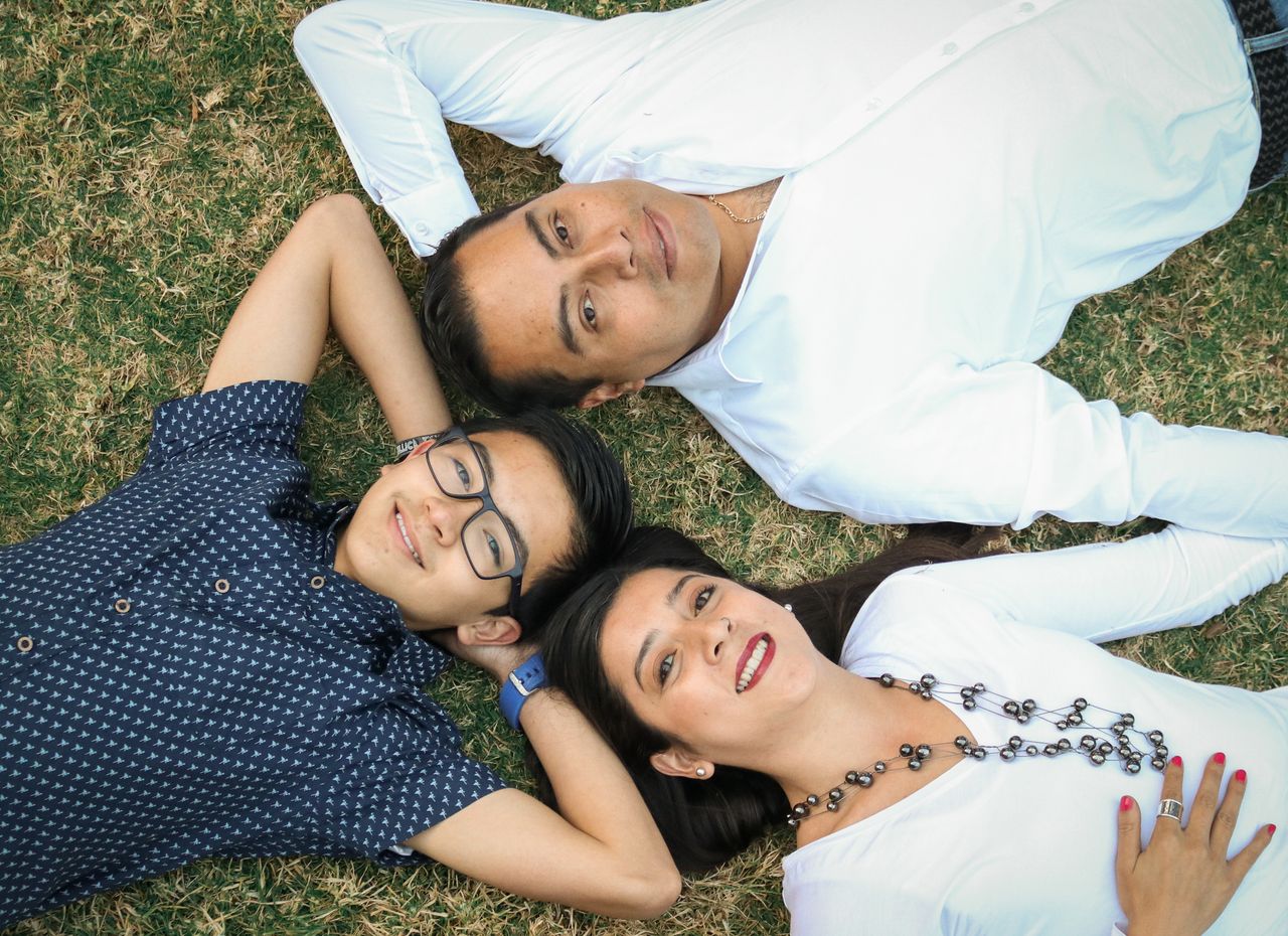 A joyful family lying on grass enjoying a sunny day together.