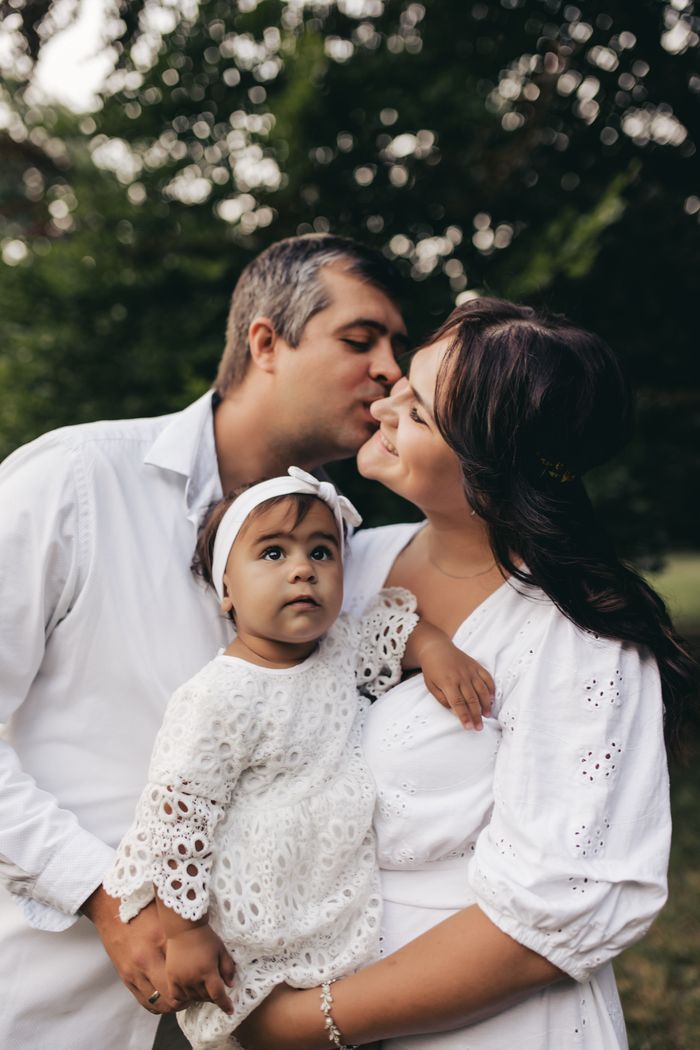 A tender family moment captured outdoors with parents embracing their young child.