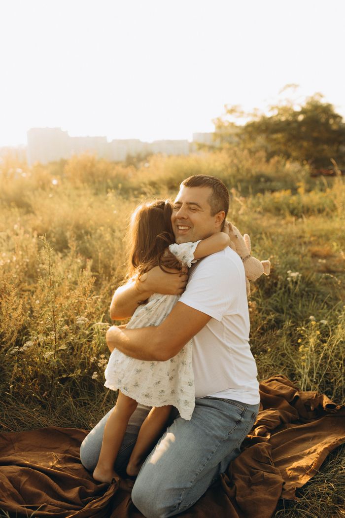 services-02 Heartwarming scene of a father and daughter hugging outdoors in a sunny field.