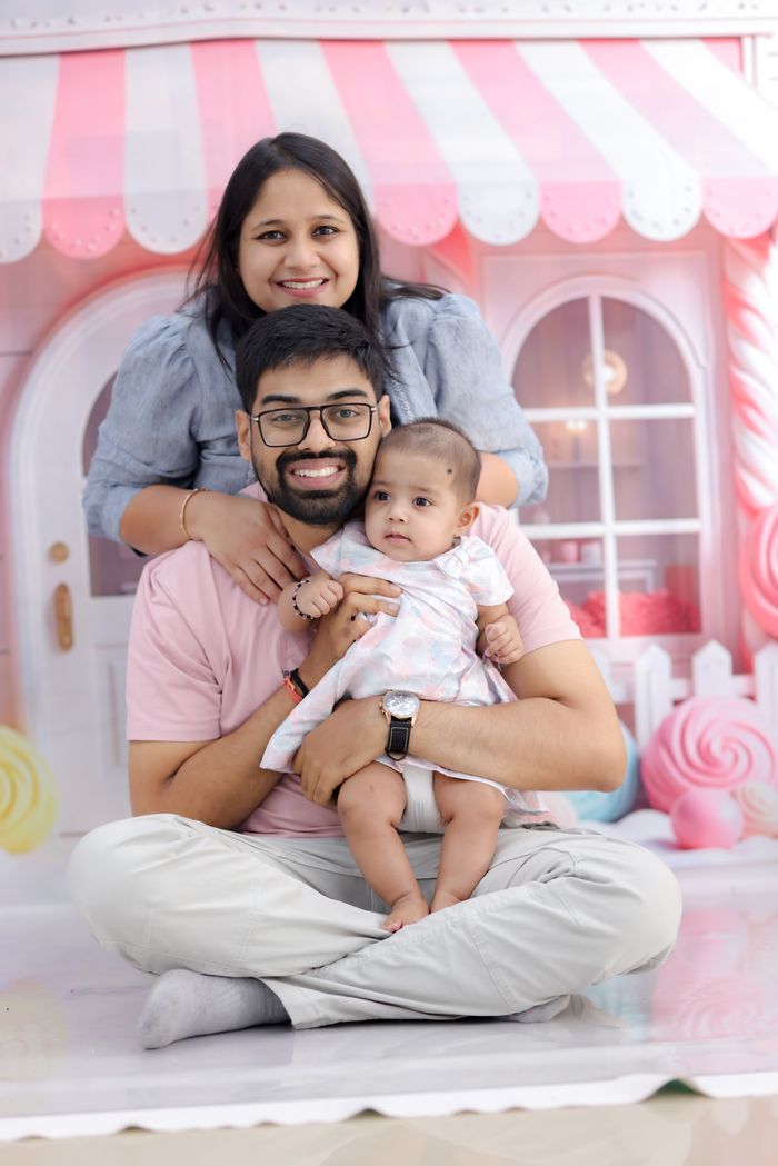 Family of three posing indoors in front of a colorful backdrop, smiling for a joyful photograph.
