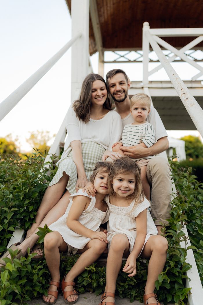 Family of five sitting on stairs, enjoying a sunny day outdoors.