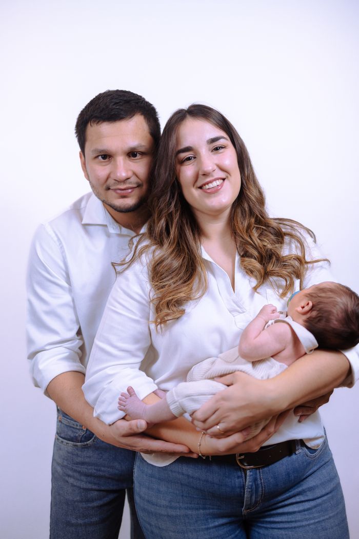 services-04 A loving family portrait featuring parents and their newborn baby in a studio setting.