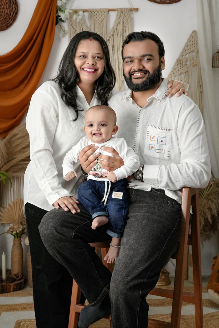 Happy family with a baby poses in a warmly decorated room with rustic elements.